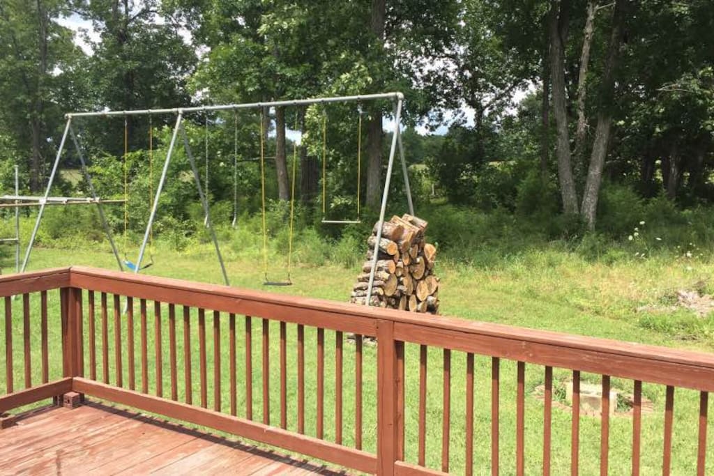 Backyard with large swingset, in-ground fire pit with wood.