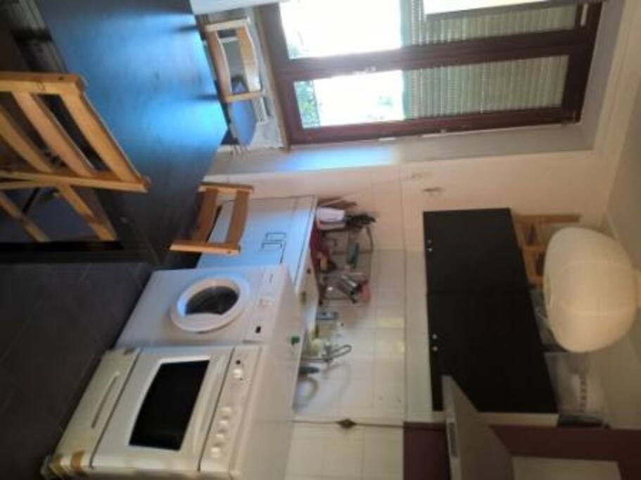 La cuisine : réfrigérateur, plaques et four à gaz, lave-linge.
