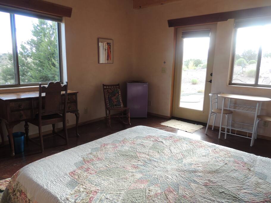 Bedroom has desk and small refrigerator and microwave.