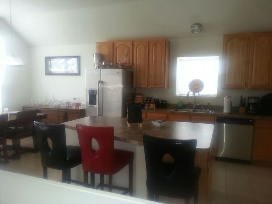 Kitchen area with large Island that seat three, dining table and bar.