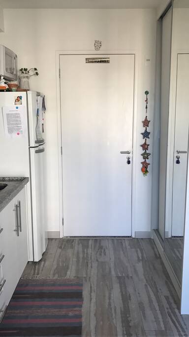Entrada com cozinha à esquerda e armário de roupas à direita.