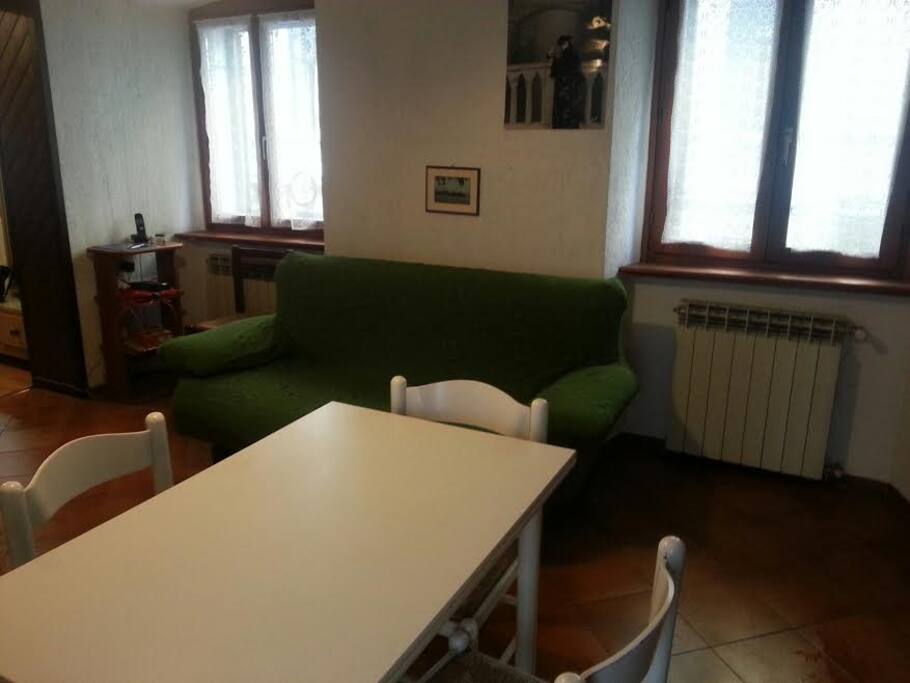 Tavolo del soggiorno con angolo cottura con divano letto matrimoniale