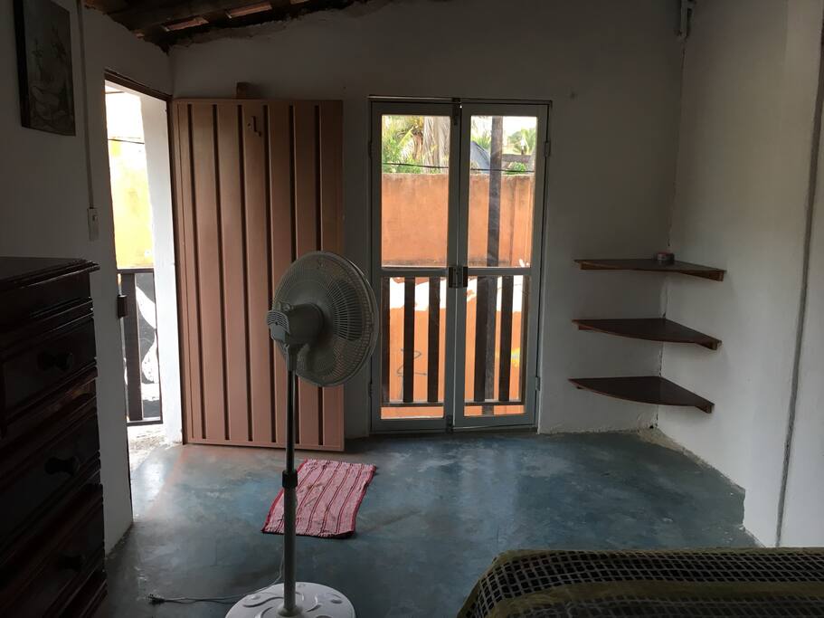 Recámara con pequeño balcón cama matrimonial ventilador y baño completo
