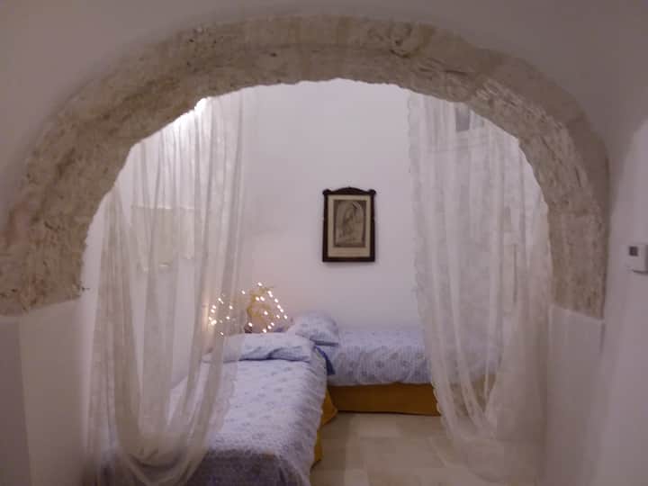 El dormitorio tiene dos camas individuales, separadas del resto de la casa por un gran arco de piedra y cortinas.