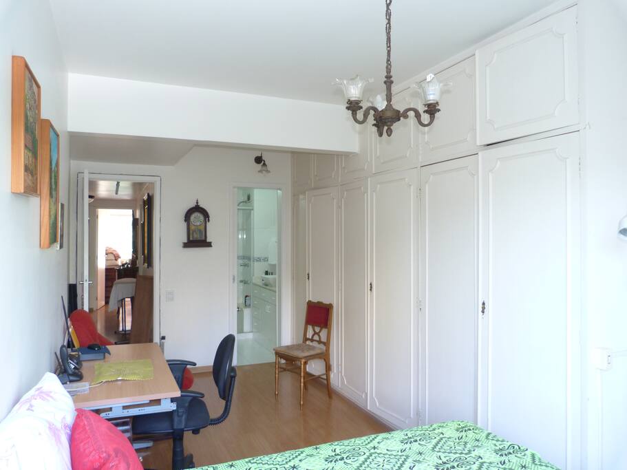 Quarto suíte amplo com mesa de trabalho e banheiro privado