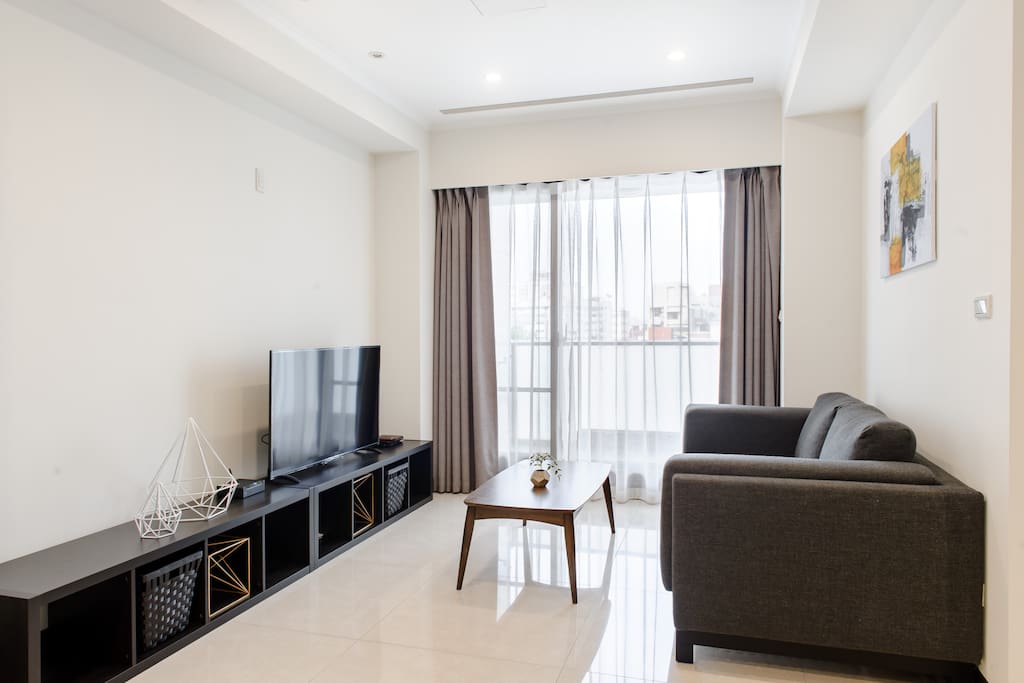 Living area with 50" TV, comfortable sofa and sunlight.