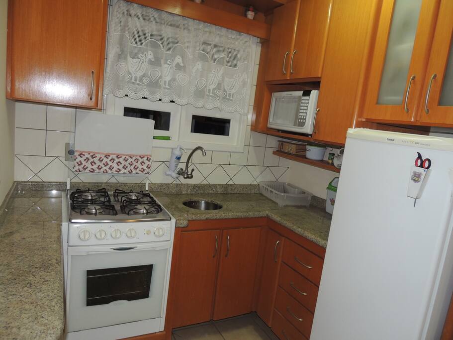 Cozinha com microondas, liquidificador, mistadeira, louças e toalhas.