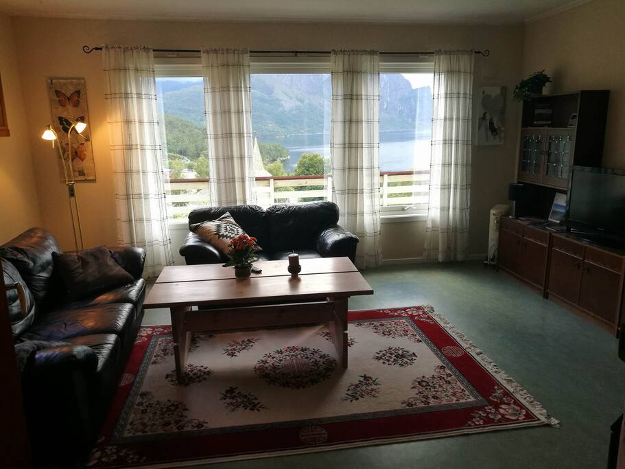 Stue med veranda og utsikt over fjorden.
The living room with a porch and a view over the fjord.