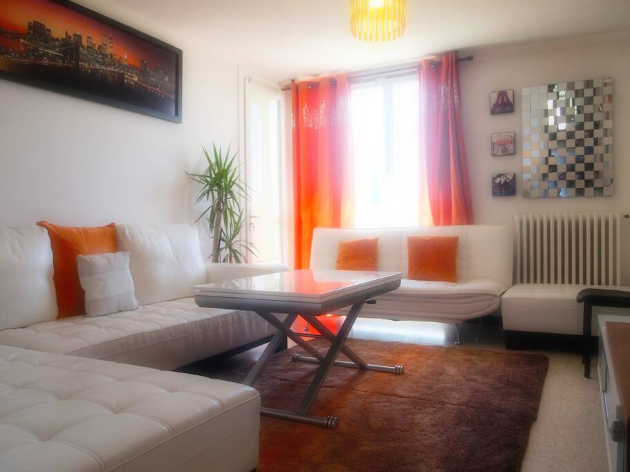 Salon avec un grand canapé d'angle en cuir blanc+écran plat+table de salle à manger extensible et un accès direct à la terrasse