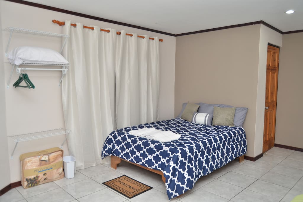 View of the main bed perfect for two people. The wood door you see at the back is the bathroom. We offer you: hangers, extra pillow, blanket & towels.