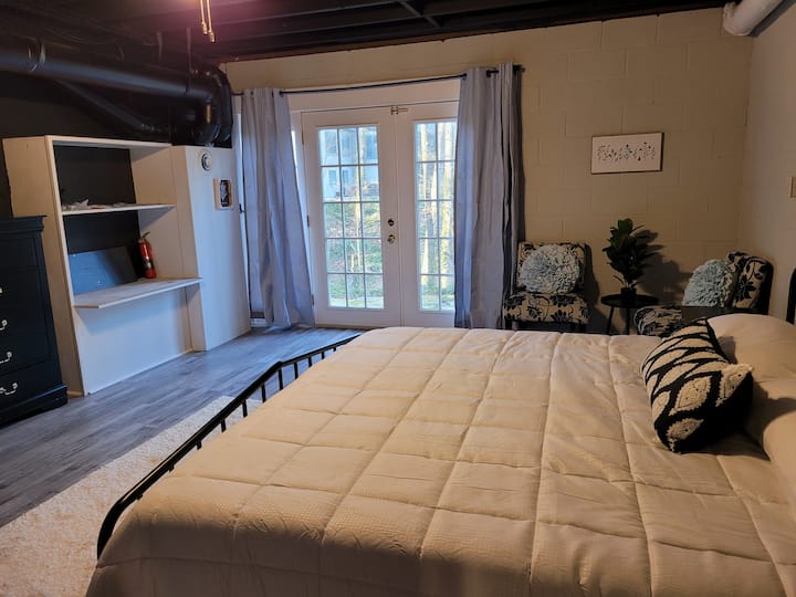 Bedroom #5, aka  industrial style master suite located downstairs with a new King Sized Sealy Foam Mattress, attached 1/2 bath, and a private entrance to the back decks as well as to the outdoor trails located just to the left of the property. 