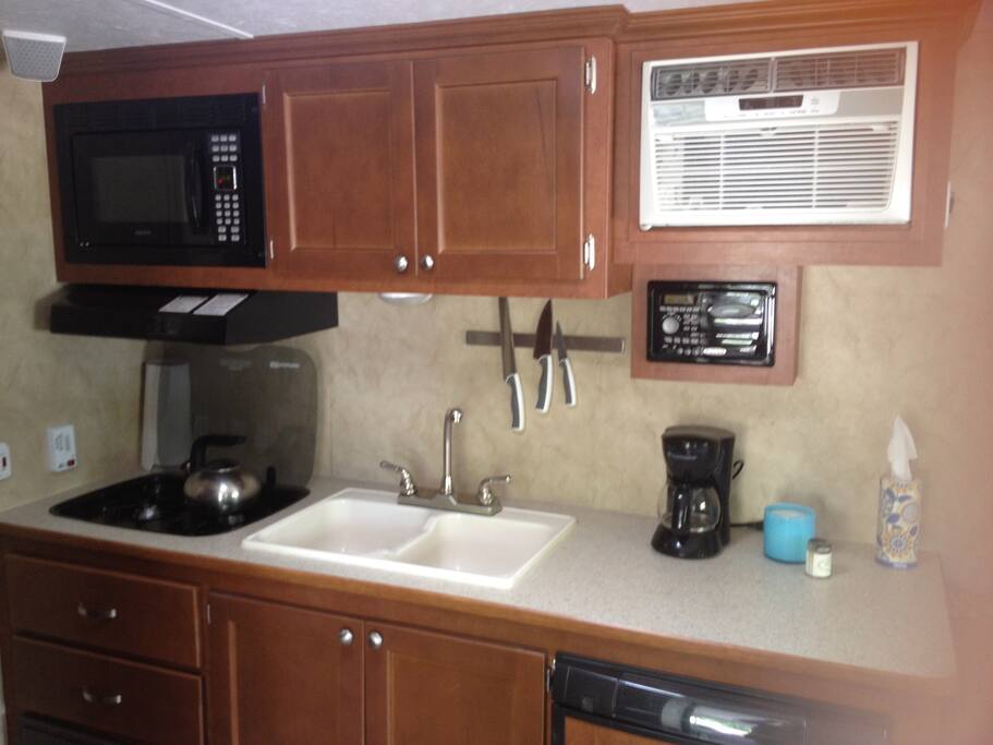Kitchen with two burner gas stove, small refrigerator, sink,and microwave.