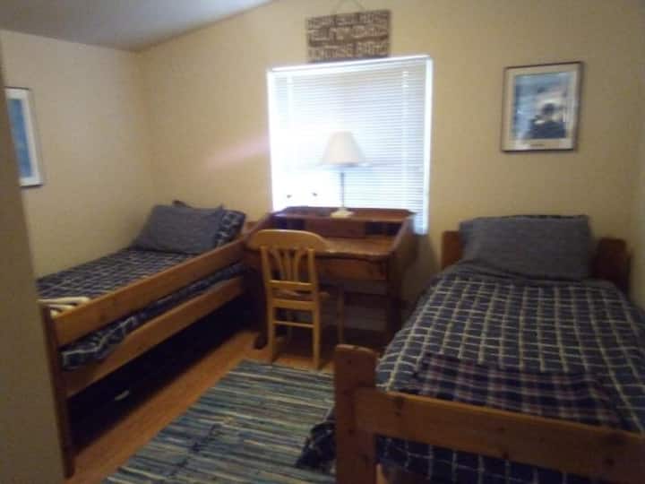 Chambre avec lits jumeaux, confortable pour les enfants et les adultes avec accès partagé à une salle de bain complète.