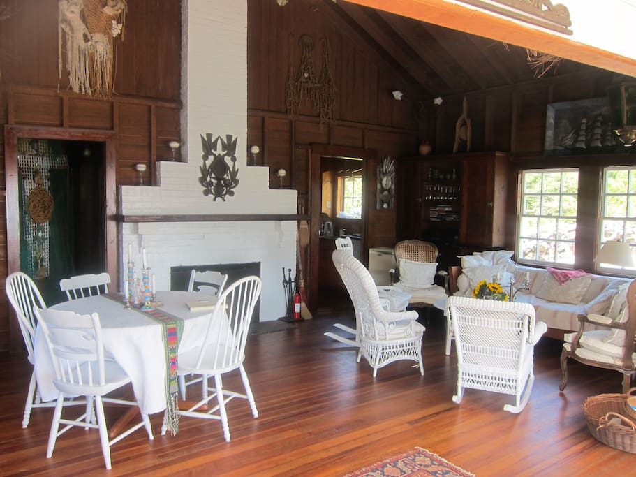 Cozy and wide open living room with dinner table. High dark wood vaulted dark wood ceiling.