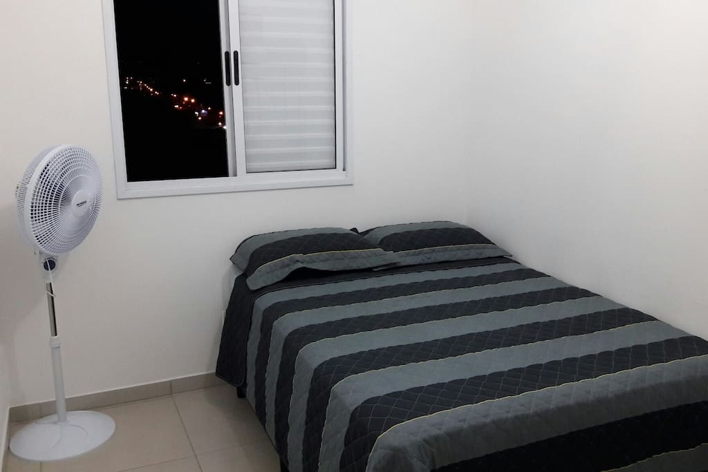 quarto com ventilador, roupa de cama e closed