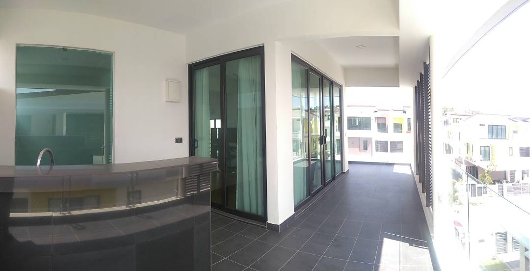 An open balcony area is shown with large glass doors providing natural light. A sleek, dark countertop serves as a bar space, while a tiled floor extends throughout. Floor-to-ceiling windows offer views of the surrounding neighborhood.
