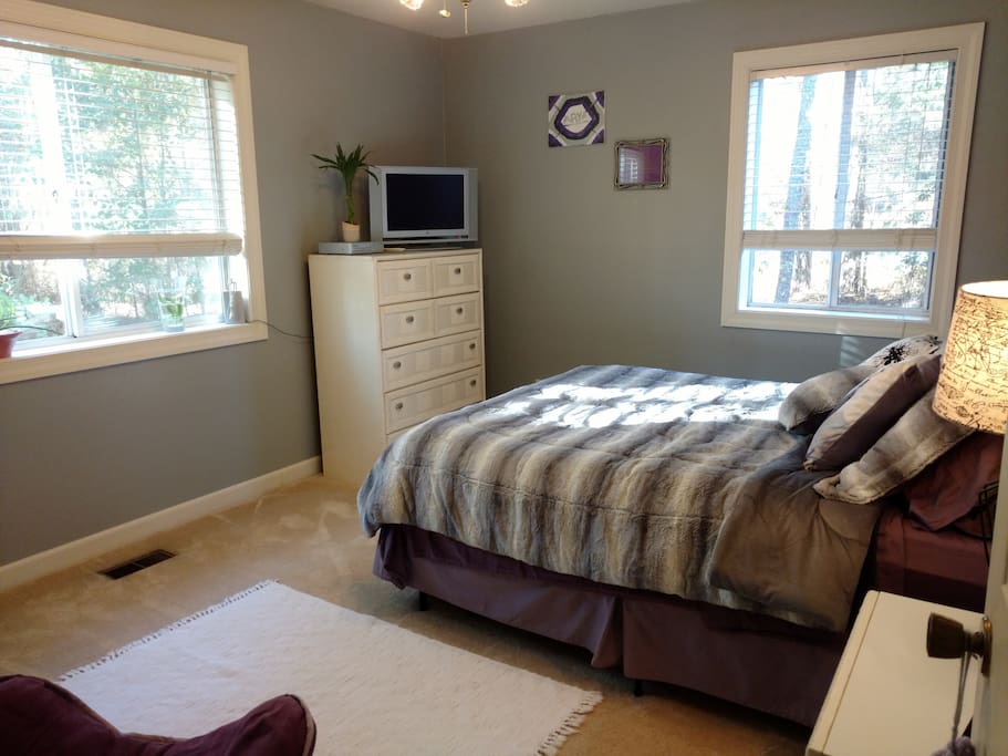 Main Guest Bedroom. Queen bed, night stand, dresser, large windows overlooking secluded, wooded setting