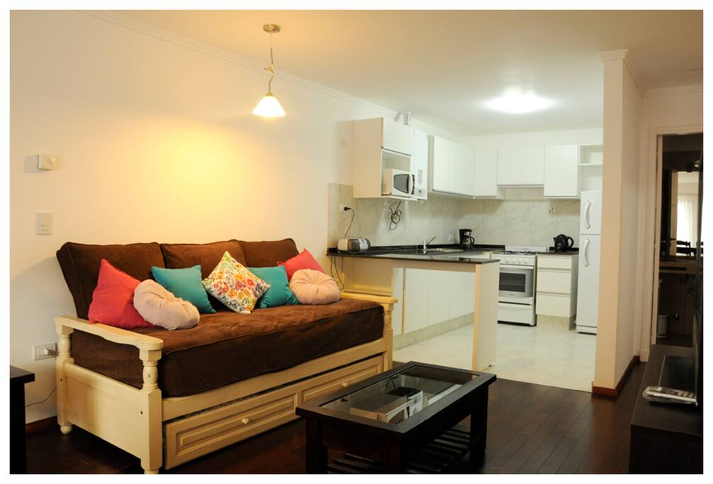 Living-comedor con sofá cama (y una cama adicional), con cocina integrada.