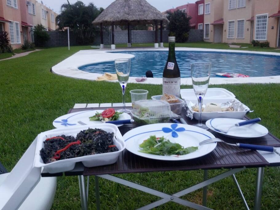 alberca compartida camastros y sillas de playa además de una mesa de jardín