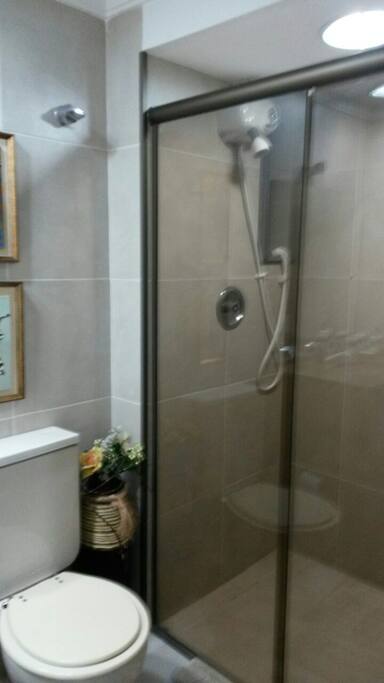 Banheiro com ducha aquecida, roupas de banho e armário. Arrumadeira