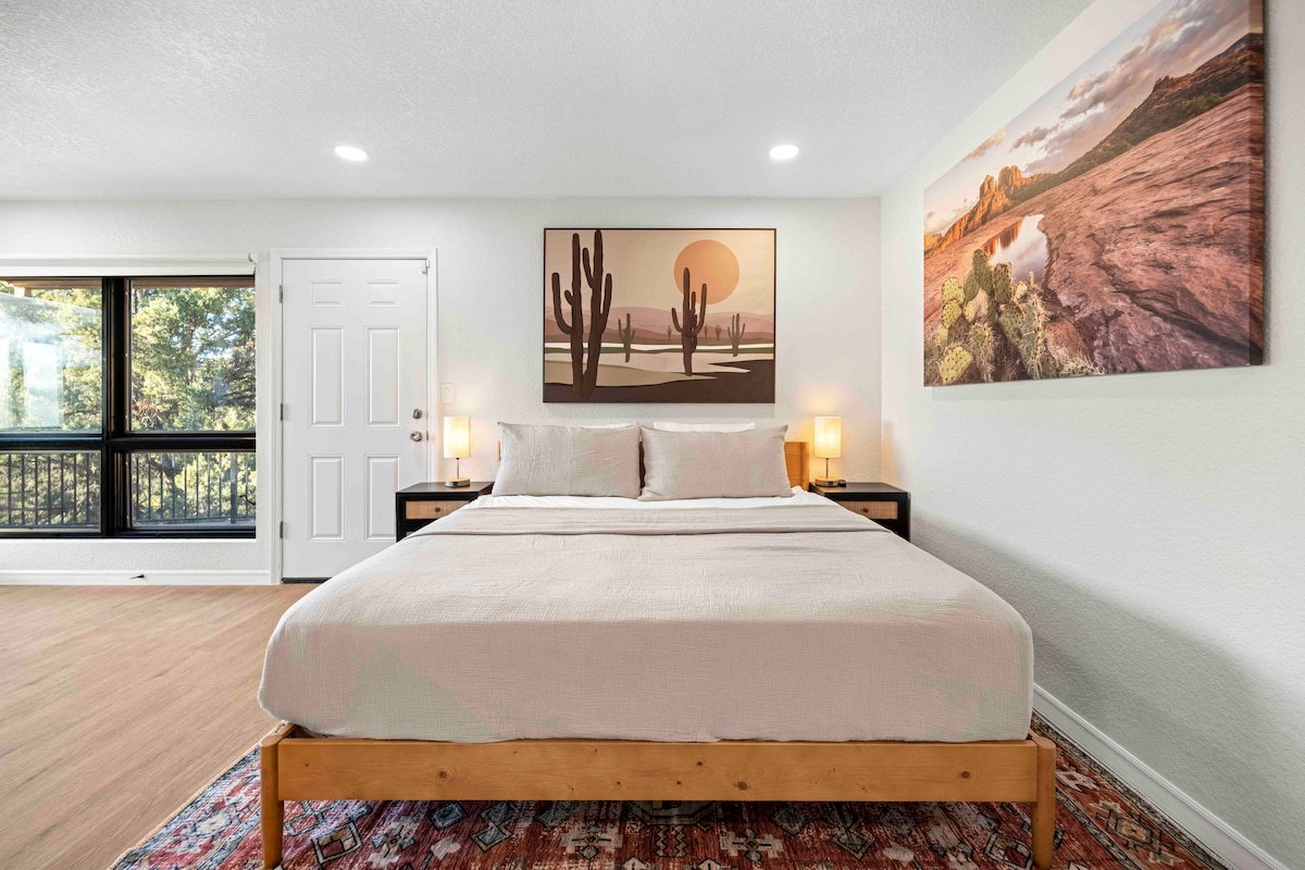 - חדר שינה מואר עם מיטת קינג סייז ויצירות אמנות מדבריות מעליו - נופים מרהיבים וחמימות מנורות ליד המיטה - חדר Airbnb מעוצב המשלב נוחות עם עיצוב טבעי  