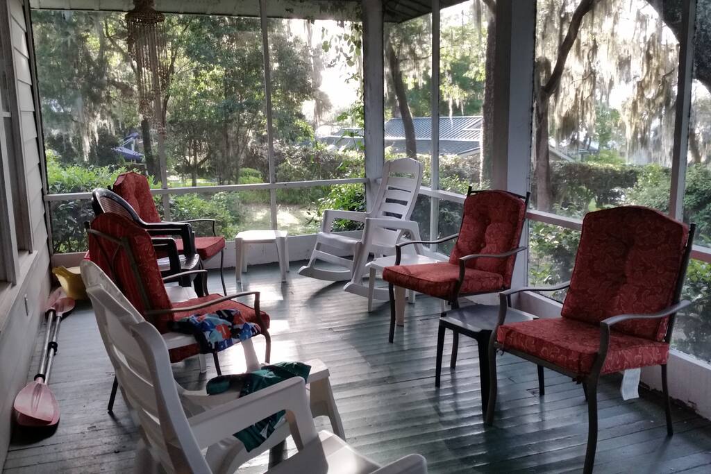 One side of screened in porch with lots of seating for conversation and watching kids play in the water.