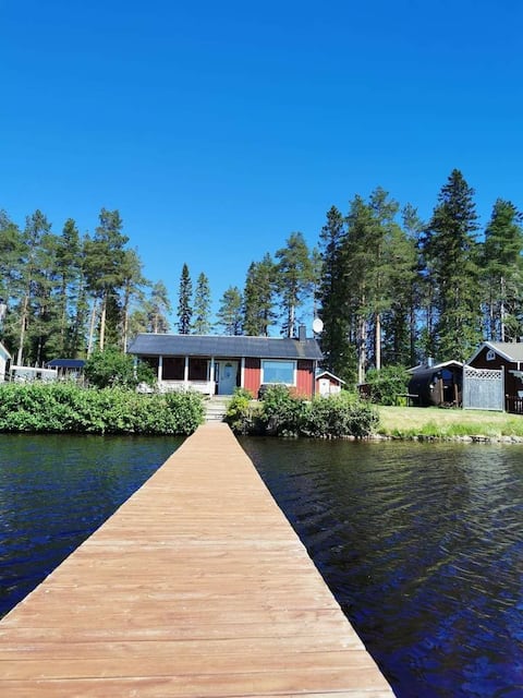 Cottage near the water with a private jetty and a boat.
