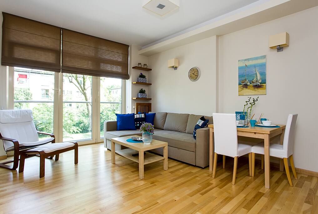 Green window view, relaxing chair and roman shades.