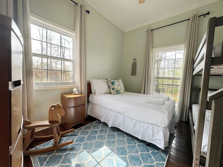 Este dormitorio tiene una cama completa y una litera individual. Las cómodas son auténticos hallazgos modernos de mediados de siglo que encajan perfectamente con la acogedora estética vintage de la cabaña de montaña de la casa. 