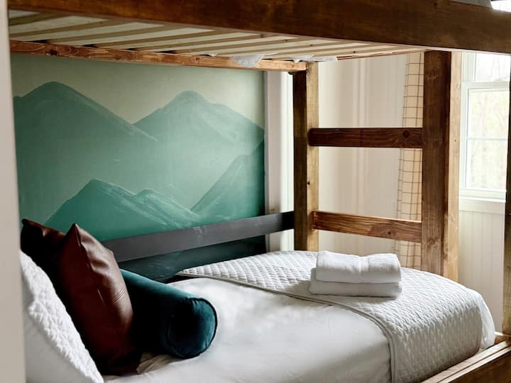 El lujo de una cabaña de montaña te espera en esta cabaña en el Coosawattee River Resort. Esta litera doble fue hecha a mano por un carpintero local y el mural fue pintado por un artista de Georgia. Comparte un baño con el dormitorio con dosel tamaño king. 
