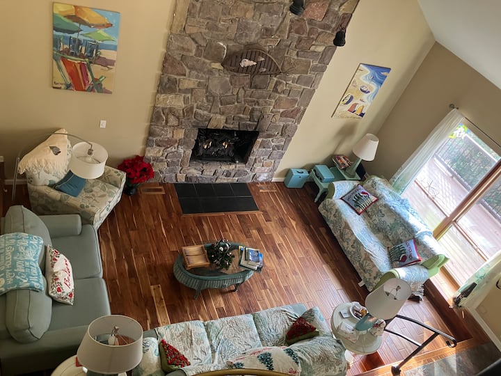 Nad veľkou obývacou izbou s množstvom miest na sedenie, 2-podlažným stropom a plynovým krbom pre chladné večery.