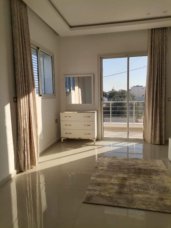 חדר מרווח ושטוף שמש, עם מיטה זוגית אחת, ארון לאחסון בגדים והזמנה אחת.