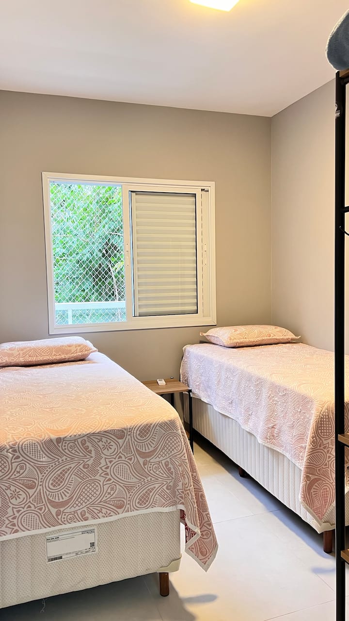 Dormitorio con 2 camas individuales, que juntas se convierten en una cama tamaño queen, aire acondicionado, armario abierto. 