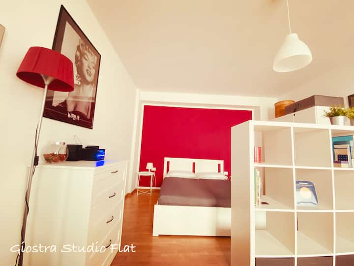 חדר שינה פתוח, מחולק על ידי כוננית, עם מיטה זוגית 160x200, שתי שידות ליד המיטה, שתי מנורות ליד המיטה, ארון דלת כפול ושידה