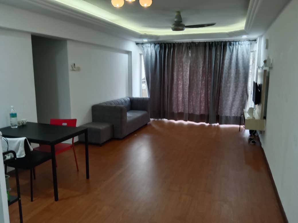 A spacious living area is equipped with a cozy gray sofa and a black dining table accompanied by red chairs. Natural light filters through the large window adorned with dark curtains. A television is mounted on the wall opposite the seating area.