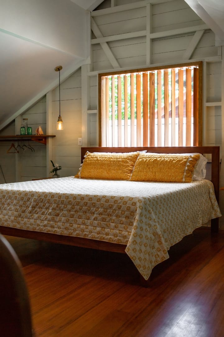 这间舒适的加大双人床套房配有毛绒床、温暖的木地板和柔和的照明，让您放松身心。 完美的度假胜地，设有私人阳台和套房浴室，让您享受宁静的丛林度假体验。