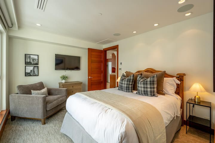 601 Queen Bedroom with television, comfortable seating and views of the village. Separate bathroom with walk-in shower