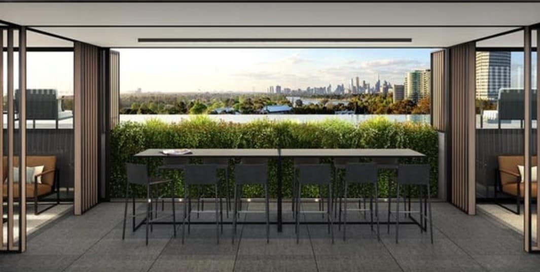 An outdoor dining area is equipped with a long table and several high-backed chairs, providing views of the surrounding greenery and city skyline. Large sliding doors create an open space, connecting the interior to the balcony, which is surrounded by potted plants.