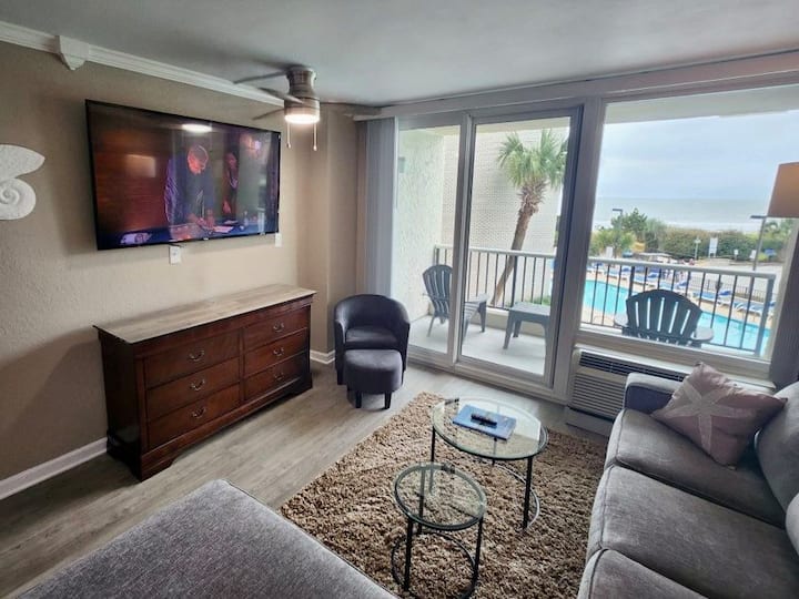 Gran televisión inteligente de pantalla plana de 65 pulgadas en la sala de estar. Asientos de comfortabe y sofá cama. Asientos nuevos en el balcón y una pequeña mesa de bebidas.