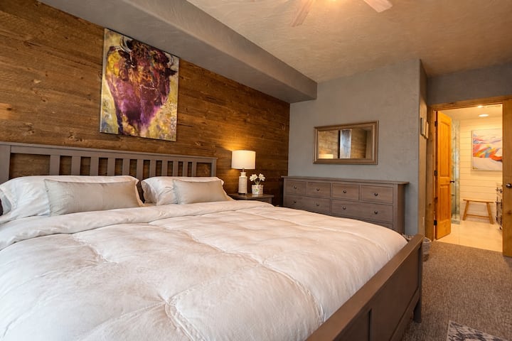 Détendez-vous dans la chambre principale accueillante, dotée d'un mobilier confortable et de détails en bois chaleureux.