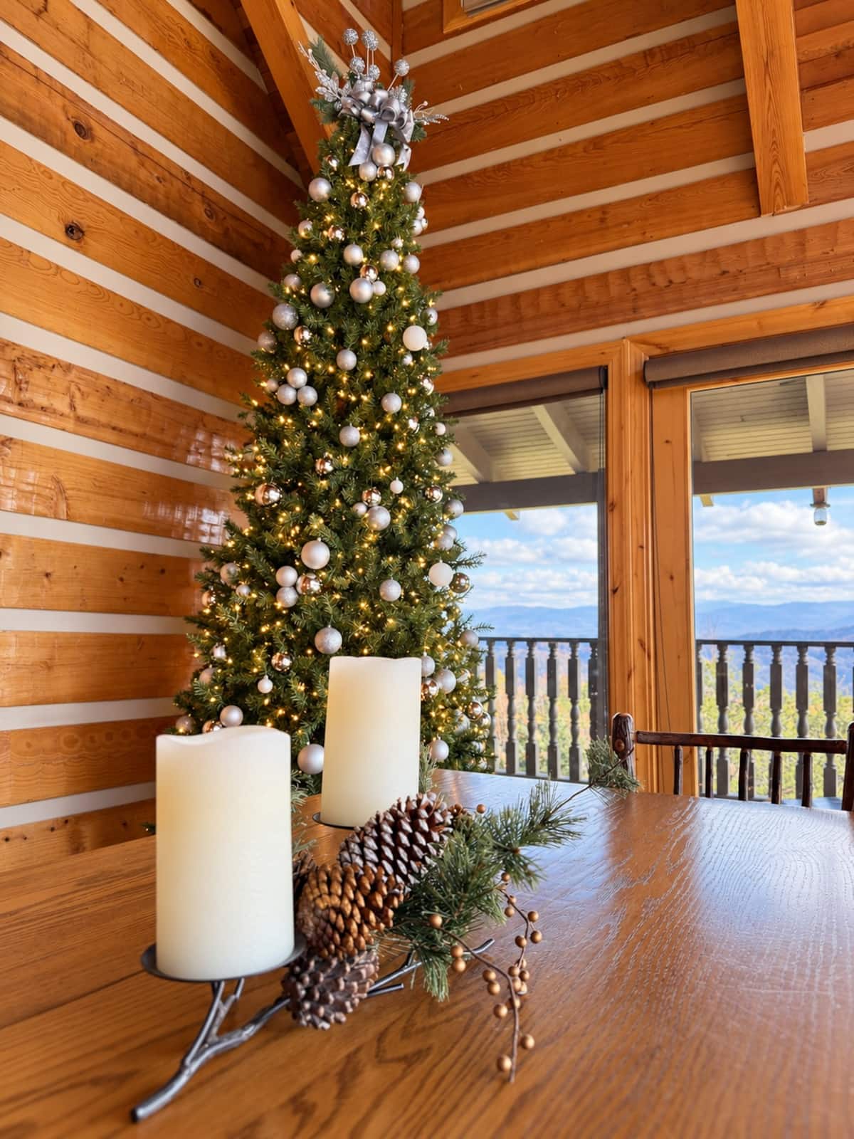 A Christmas tree and festive dining table beside the mountain-view windows.