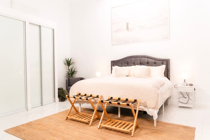 Bright, serene primary bedroom featuring a plush king bed, warm wood accents, and a calming neutral palette—designed for rest after a day exploring Old San Juan.