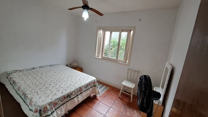 Spavaća soba s jednim bračnim krevetom. Ima stropni i podni ventilator.