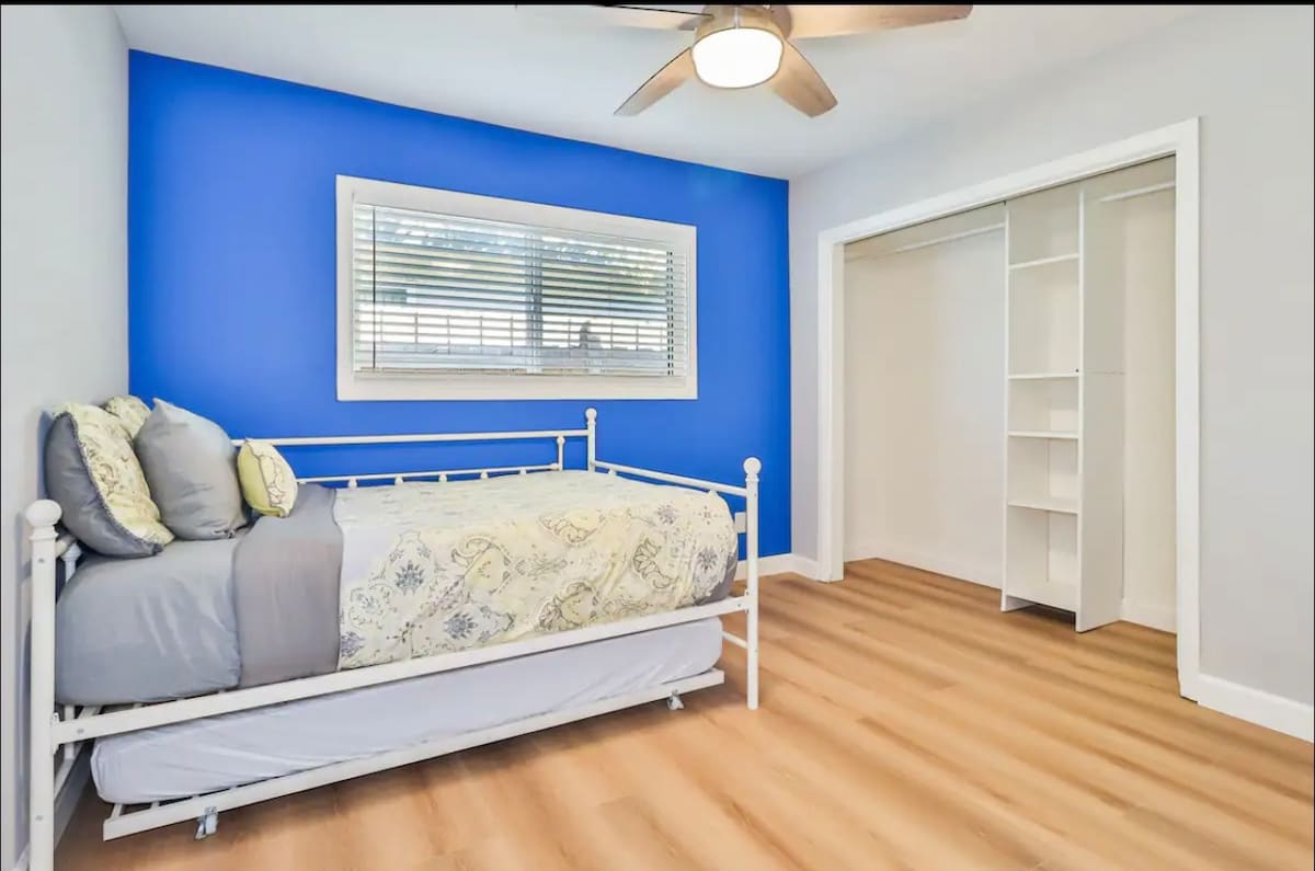 Habitación luminosa con banco acolchado y mesita de noche con espejo.