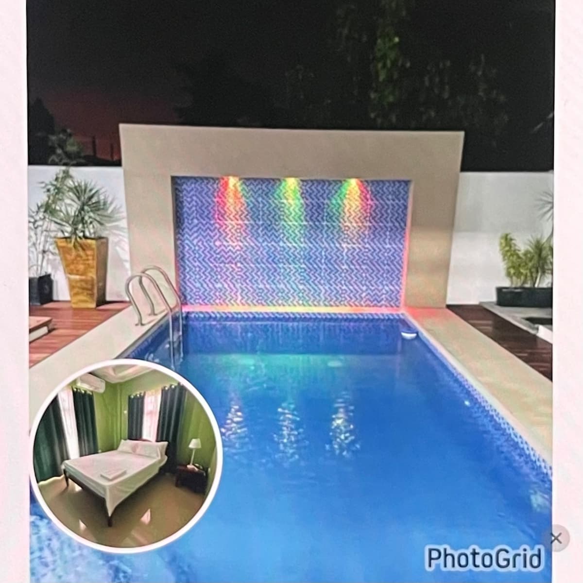 An inviting pool glistens under evening lights, featuring a colorful water wall that adds a vibrant touch. Lush greenery surrounds the area, complementing the tranquil setting. A small inset image displays a bright sleeping area, equipped with a spacious bed and large windows draped in green curtains.