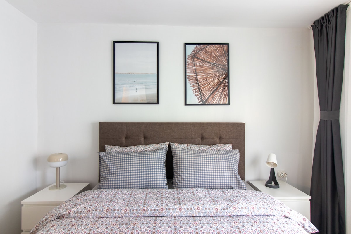 חדר שינה ראשי מסוגנן עם אומנות מודרנית ומיטה נוחה.