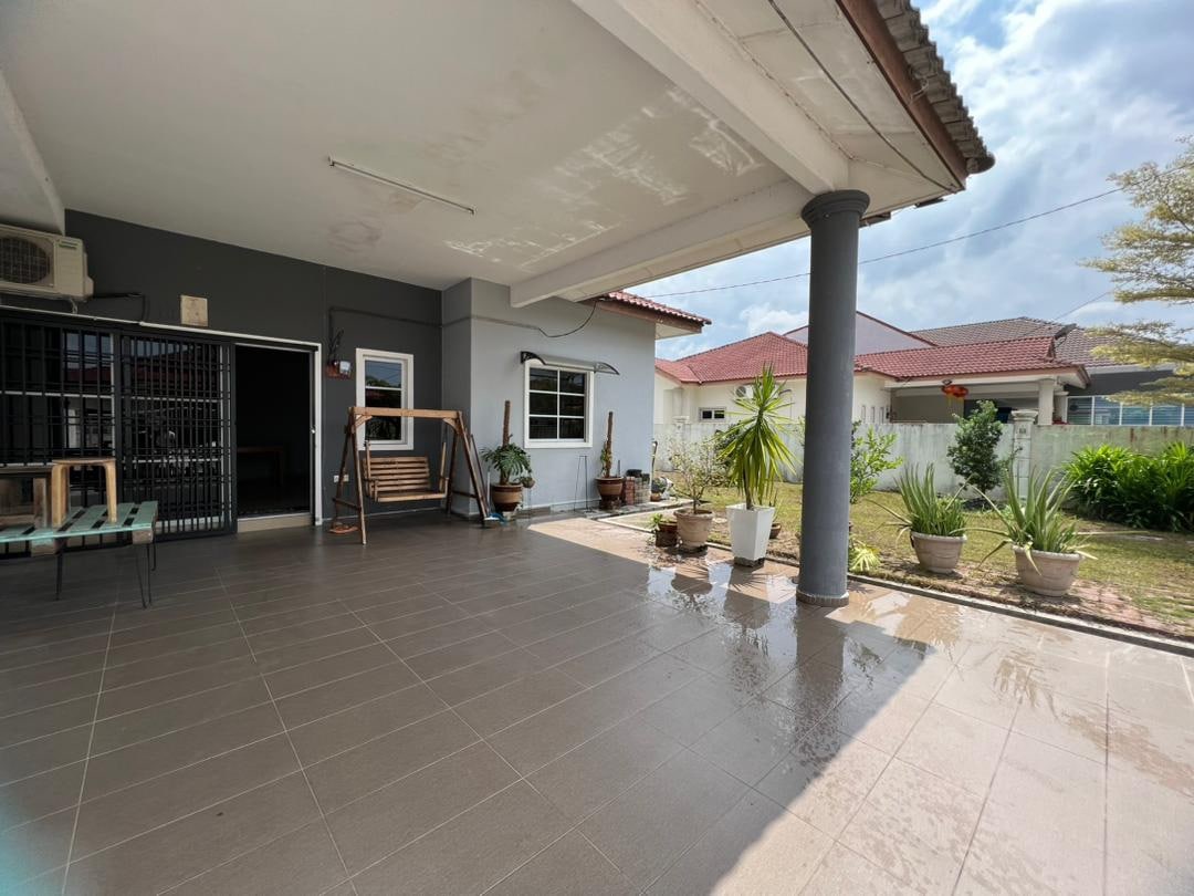 A spacious outdoor patio area features modern tiles and is complemented by potted plants. A wooden swing adds a relaxed touch, while the gray walls and pillars provide a sturdy backdrop. Natural light flows in from the nearby windows, highlighting the inviting space.