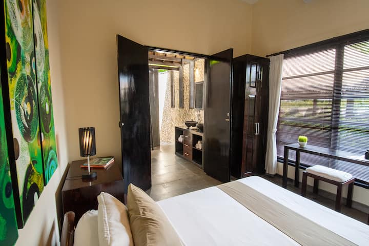 A quiet and private bedroom designed for restful stays, with direct access to its ensuite bathroom. Clean lines, warm materials and soft light create a calm atmosphere, ideal for guests seeking a more secluded space within the villa.