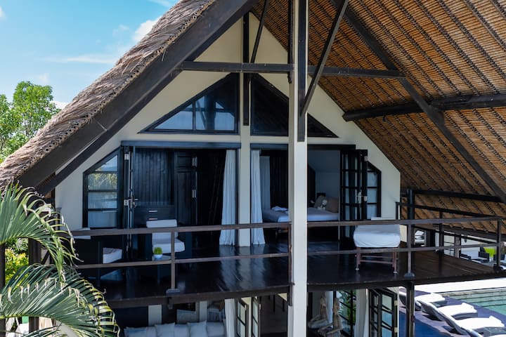 Private upper-floor bedroom with its own terrace overlooking the garden and ocean. Includes a coffee corner with comfortable seating, ideal for reading or enjoying quiet mornings. Large bed and ensuite bathroom complete the space.