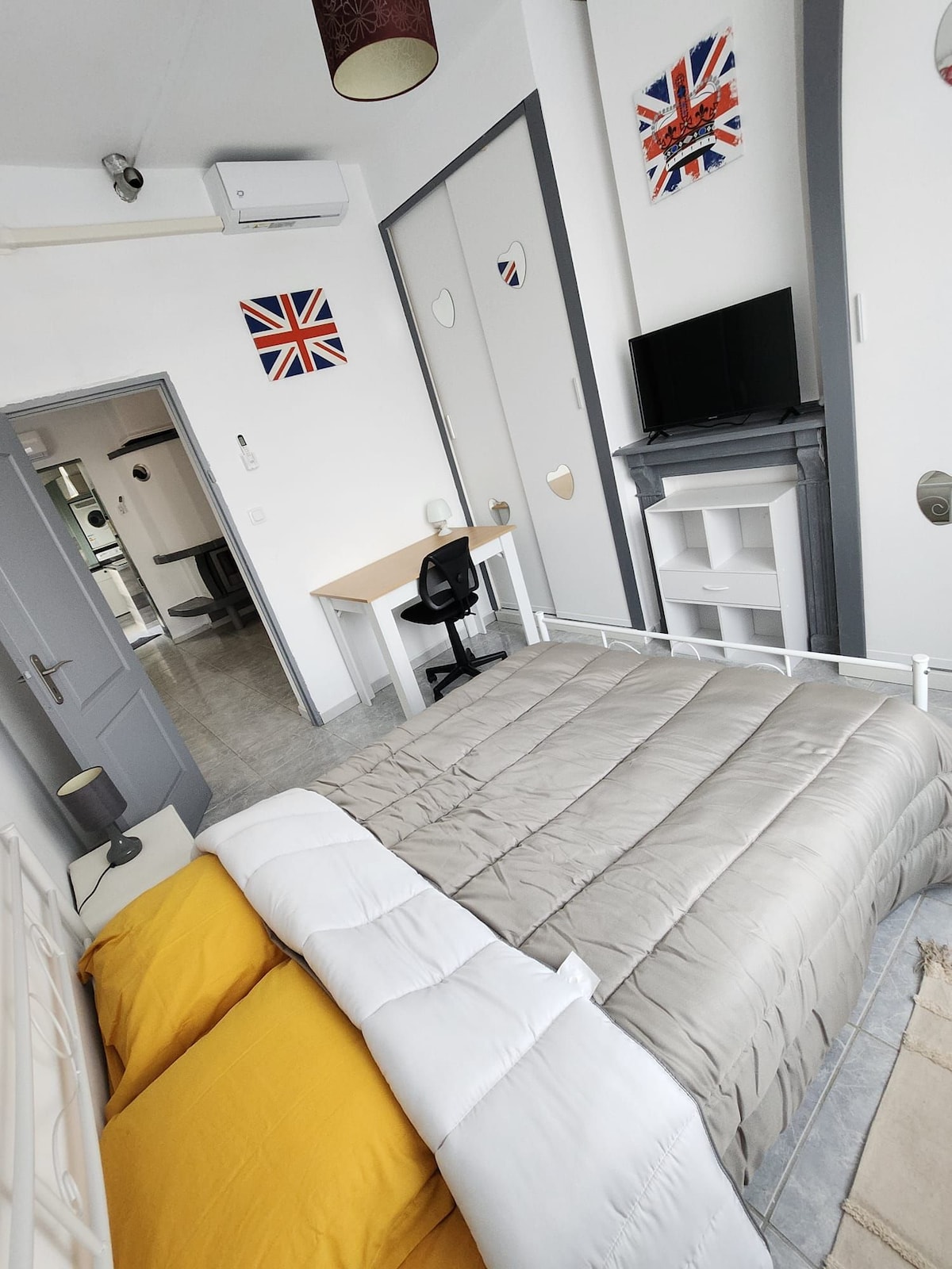 Lagere slaapkamer met tweepersoonsbed, tv en bureau.